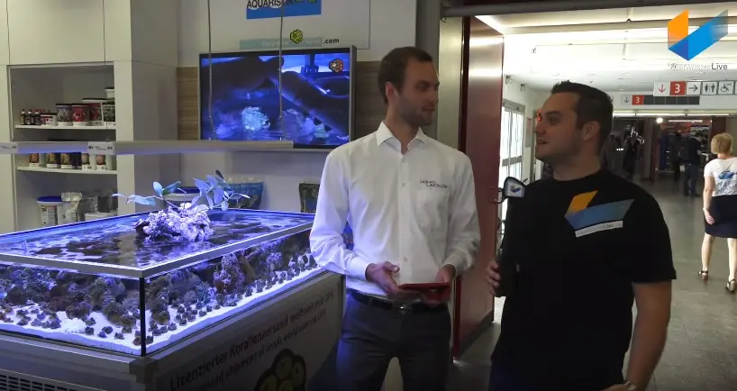 Interview am aquaLEDs-Messestand vor einem beleuchteten Riffaquarium